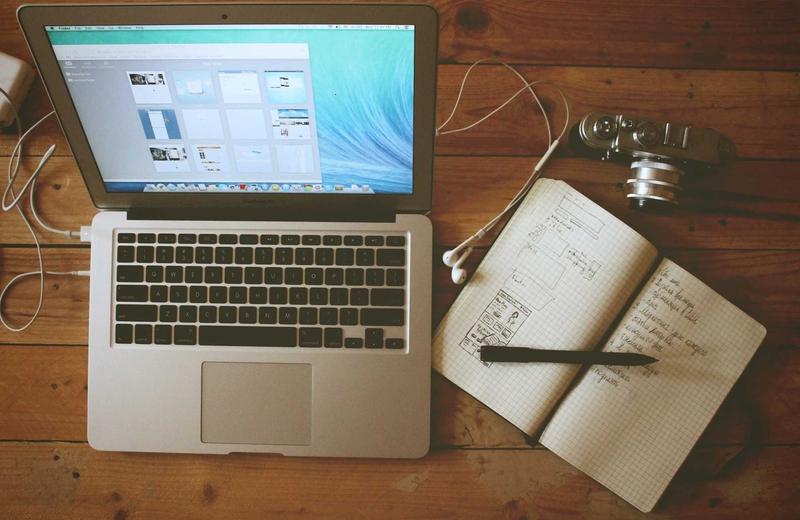 Laptop y libreta con notas sobre una mesa de trabajo
