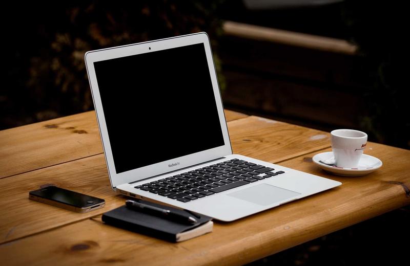Laptop sobre un escritorio de madera junto a una taza de café