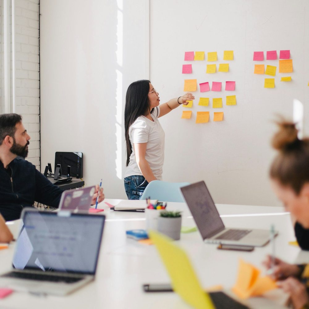 Equipo de emprendedores en un taller de estrategia, con notas adhesivas en la pared y laptops sobre la mesa